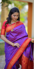 Woman wearing a traditional purple and orange saree with gold jewelry outdoors.