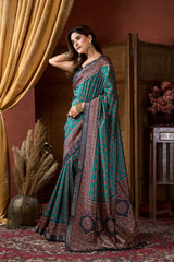 Woman in a traditional saree standing in a room with decorative elements.