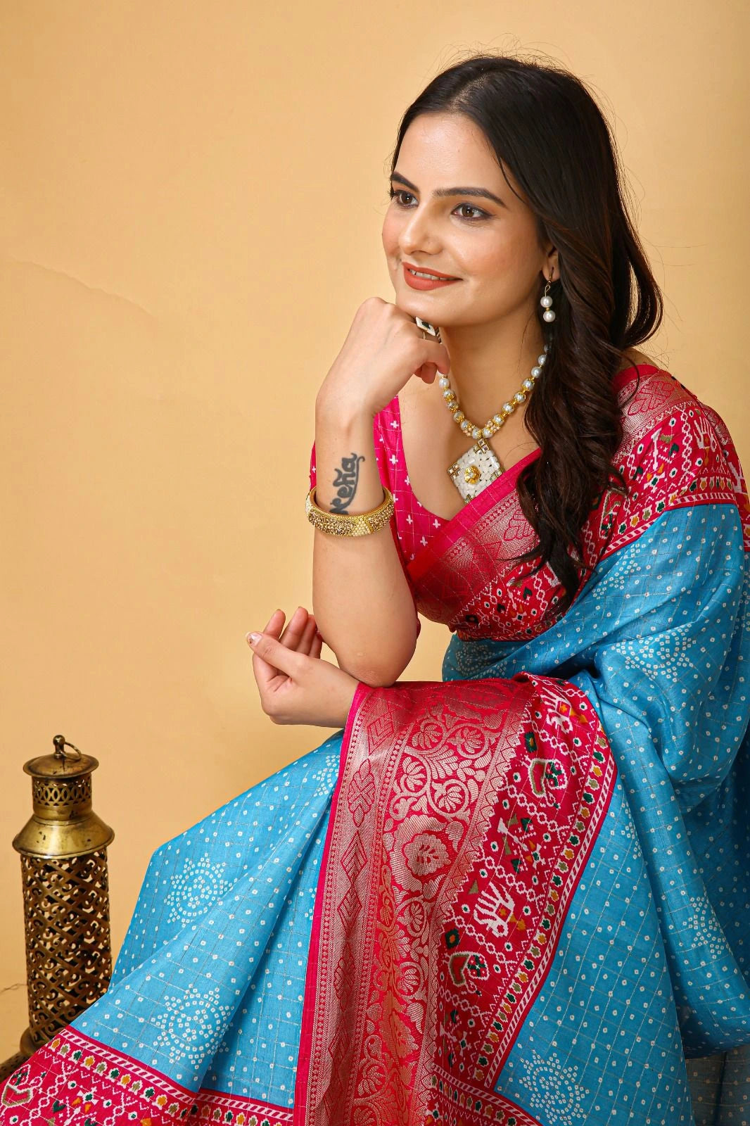 Woman wearing a traditional blue and pink saree with a beige background