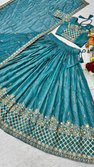 Teal embroidered traditional outfit with gold details on a light gray surface.