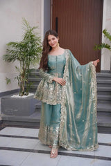 Woman in a light blue traditional outfit with a matching dupatta, standing indoors.