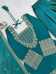 Teal traditional outfit with gold embroidery on a textured white background