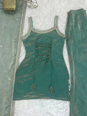 Teal outfit with lace-up front and decorative elements on a textured white background