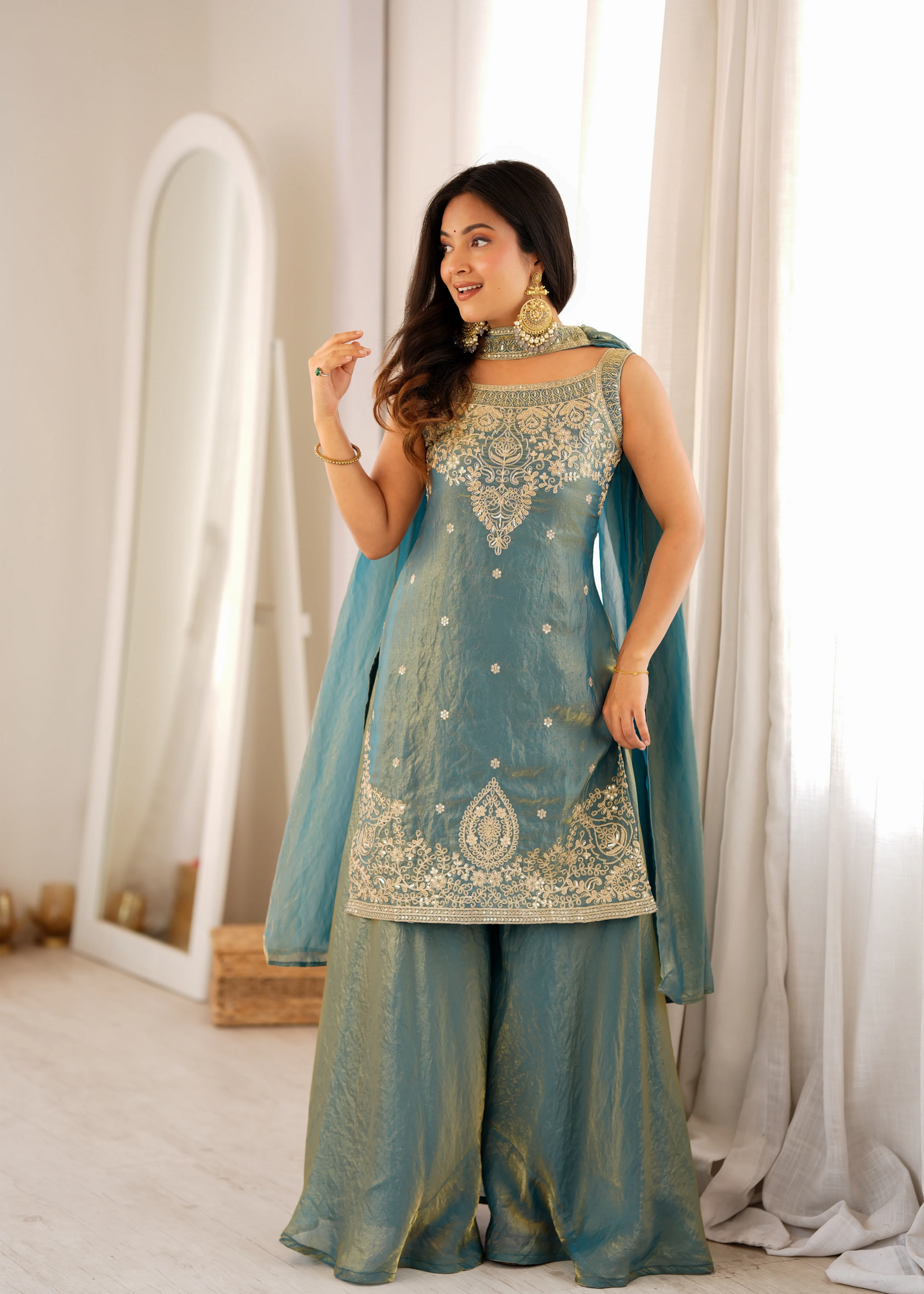 Woman wearing a traditional outfit with intricate designs in a well-lit room.