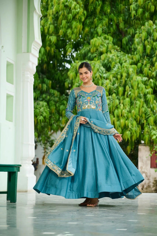 Woman in a blue traditional outfit with greenery in the background