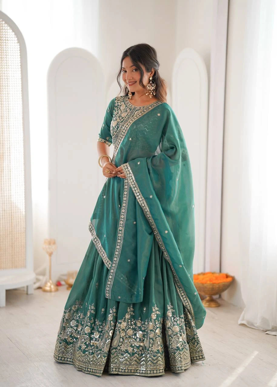 Woman wearing a teal saree with white patterns in a minimalistic room.