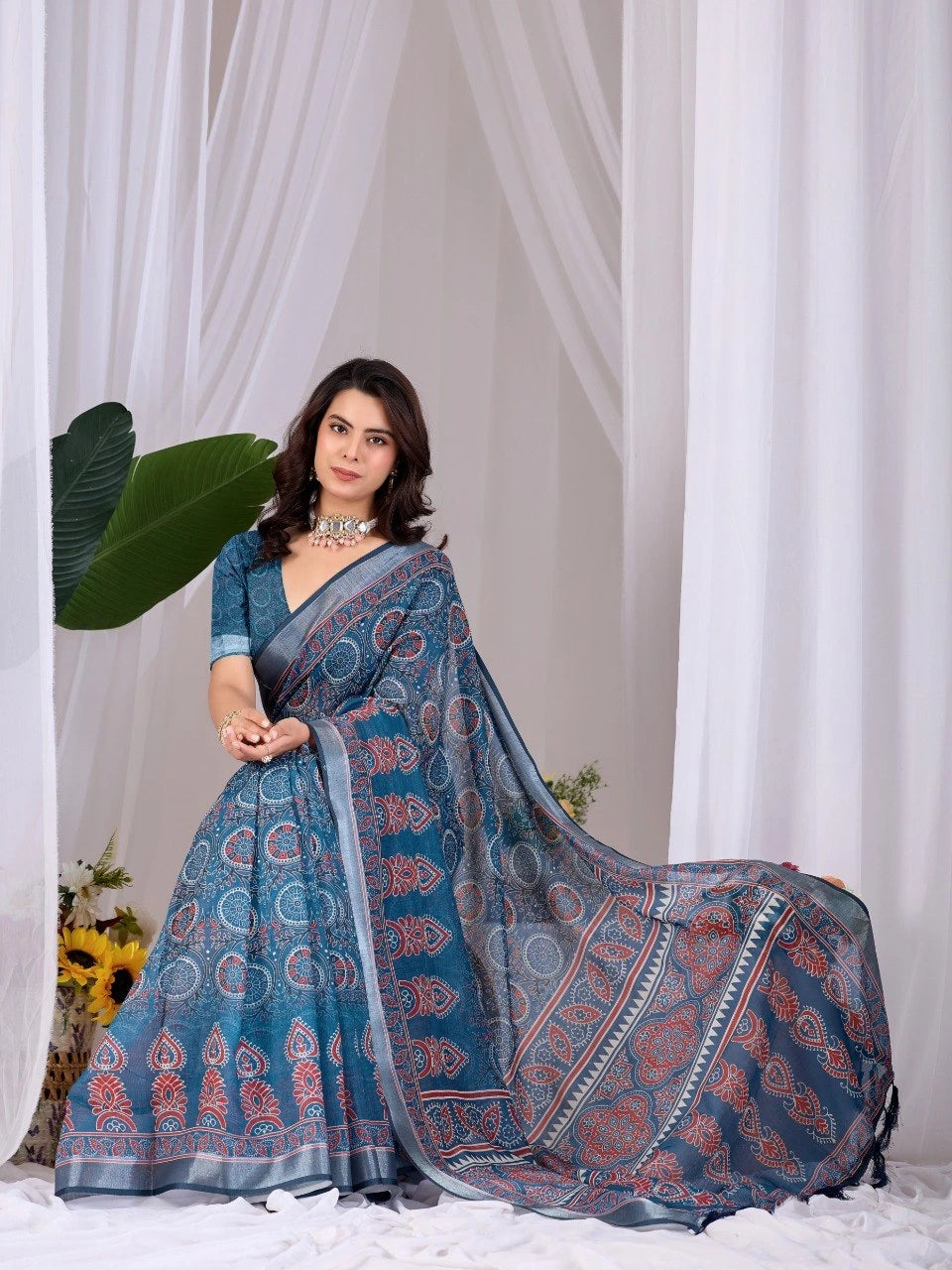 Woman wearing a blue saree with a white curtain background