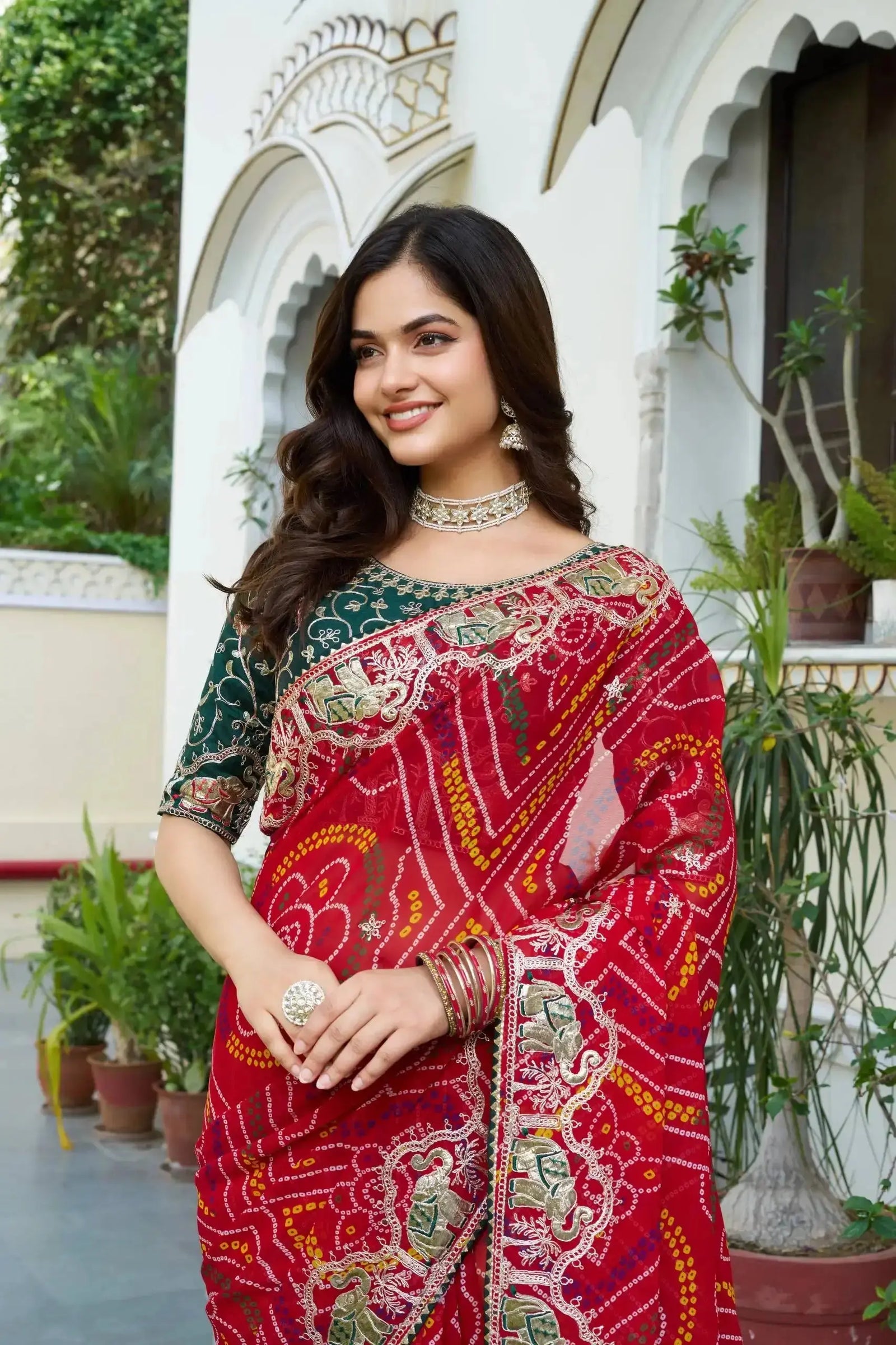 Red Gota Patti Saree styled with flared pleats against palace pillar