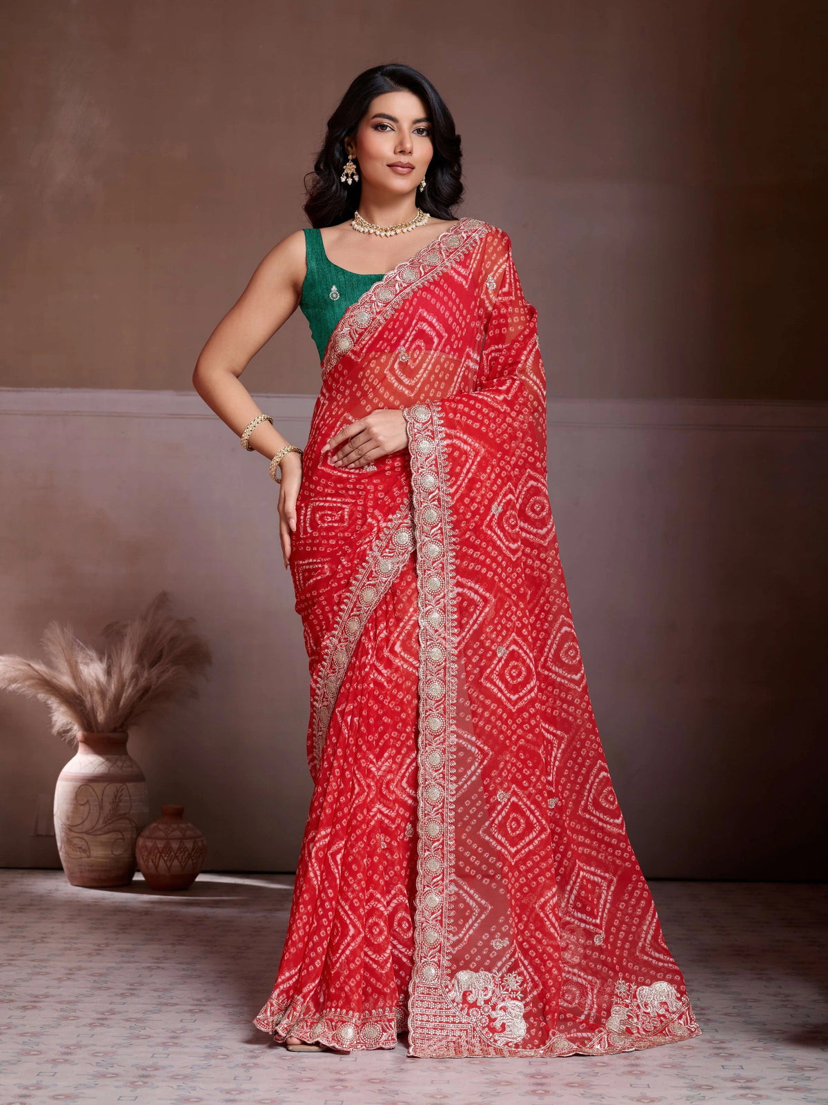 Woman wearing a red saree with a white pattern against a neutral background