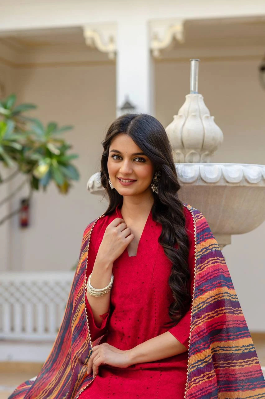 Woman in a red outfit with a colorful shawl sitting outdoors.