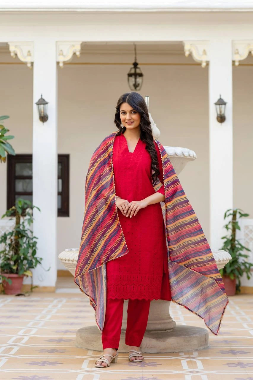 Woman in a red outfit with a colorful shawl standing in an indoor setting.