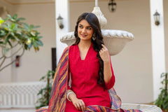 Woman in a red outfit with a colorful shawl sitting outdoors.