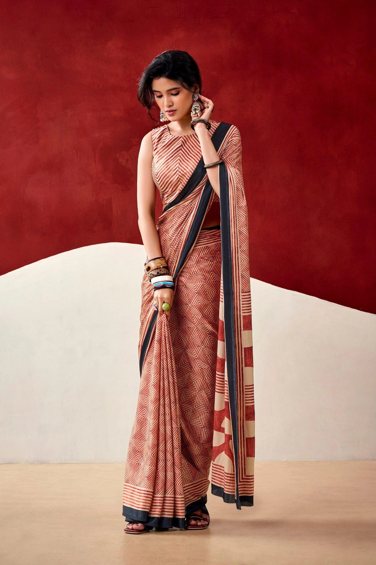 Woman wearing a traditional saree against a red and beige background