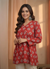 Woman wearing a red floral patterned dress against a beige curtain background