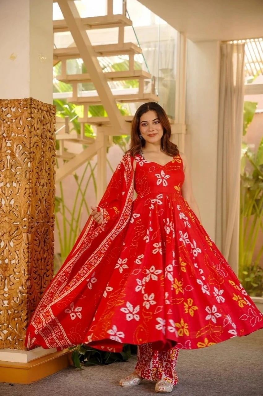 Woman wearing a red floral dress standing indoors with decorative elements in the background