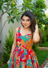 Woman in a colorful dress standing outdoors with greenery in the background