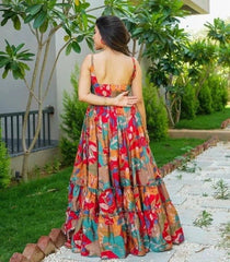 Woman in a colorful floral dress standing outdoors with greenery around
