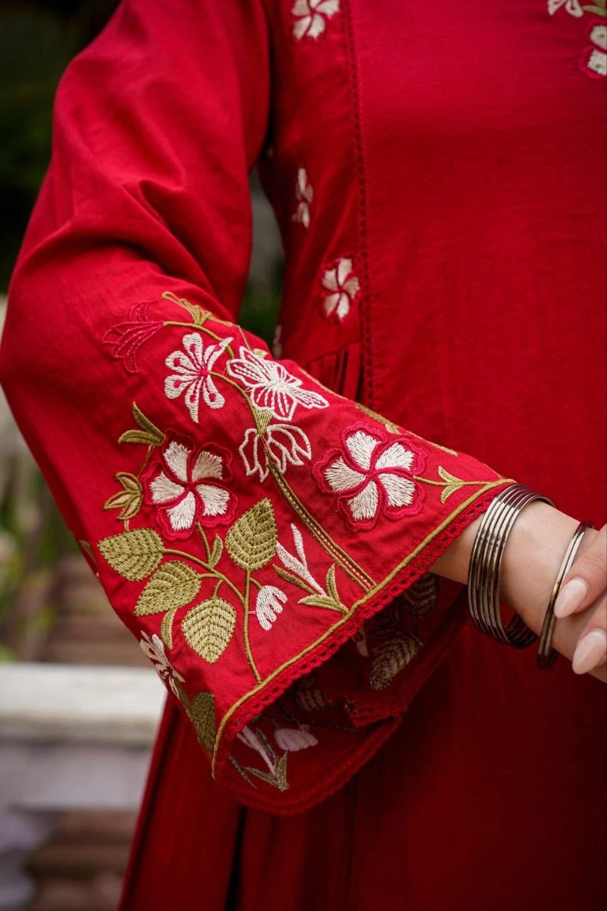 Red garment with floral embroidery and gold accents, worn by a person.