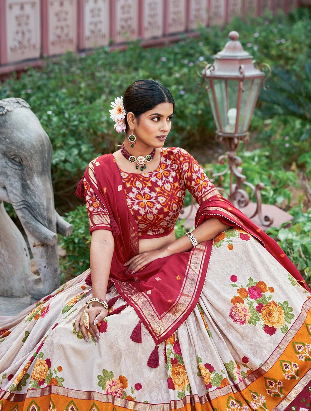 Woman in traditional Indian attire with floral patterns in a garden setting
