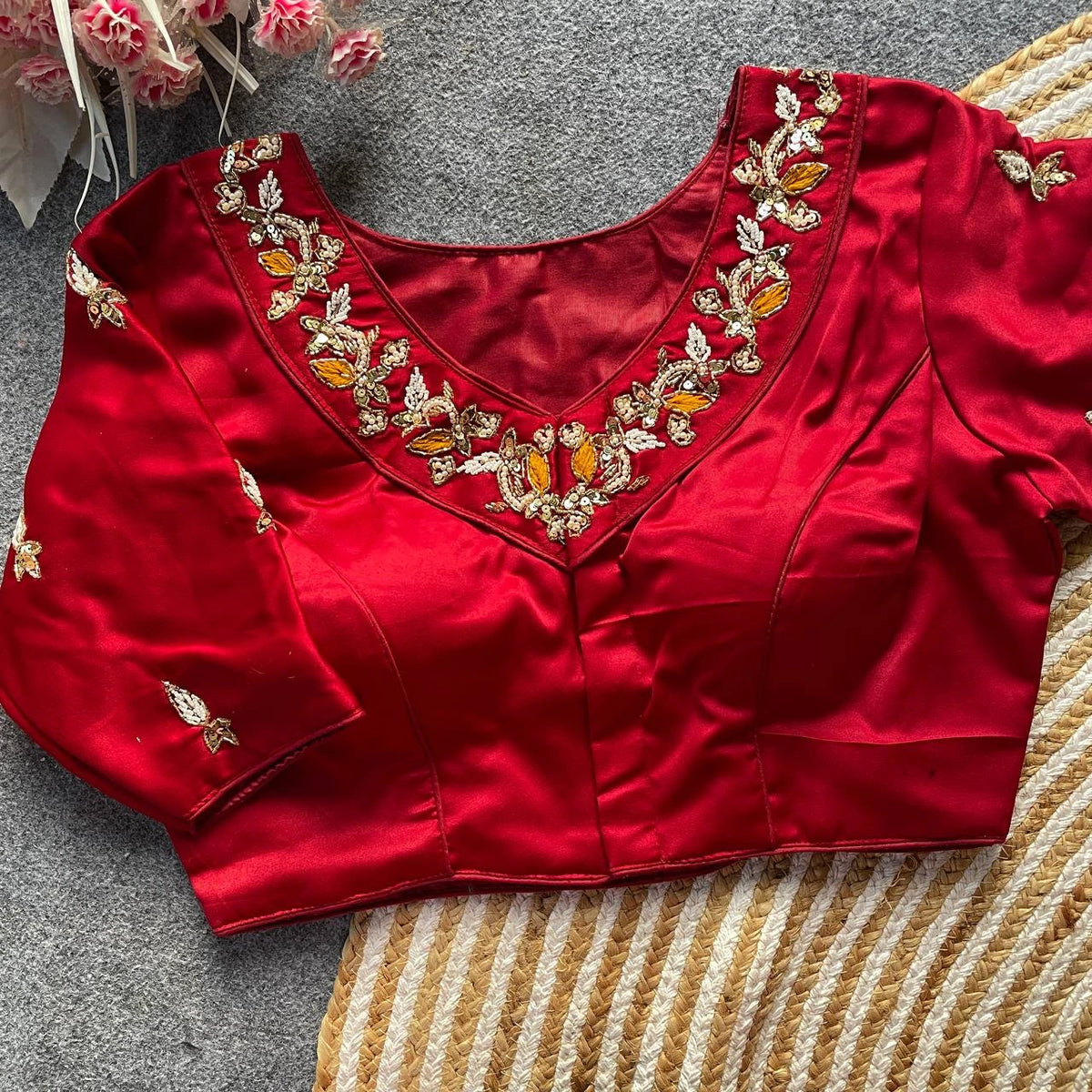Red blouse with gold and orange embroidery on a textured surface