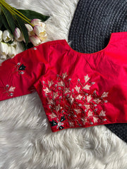 Red embroidered top on a white fur surface with flowers and a black knitted item.