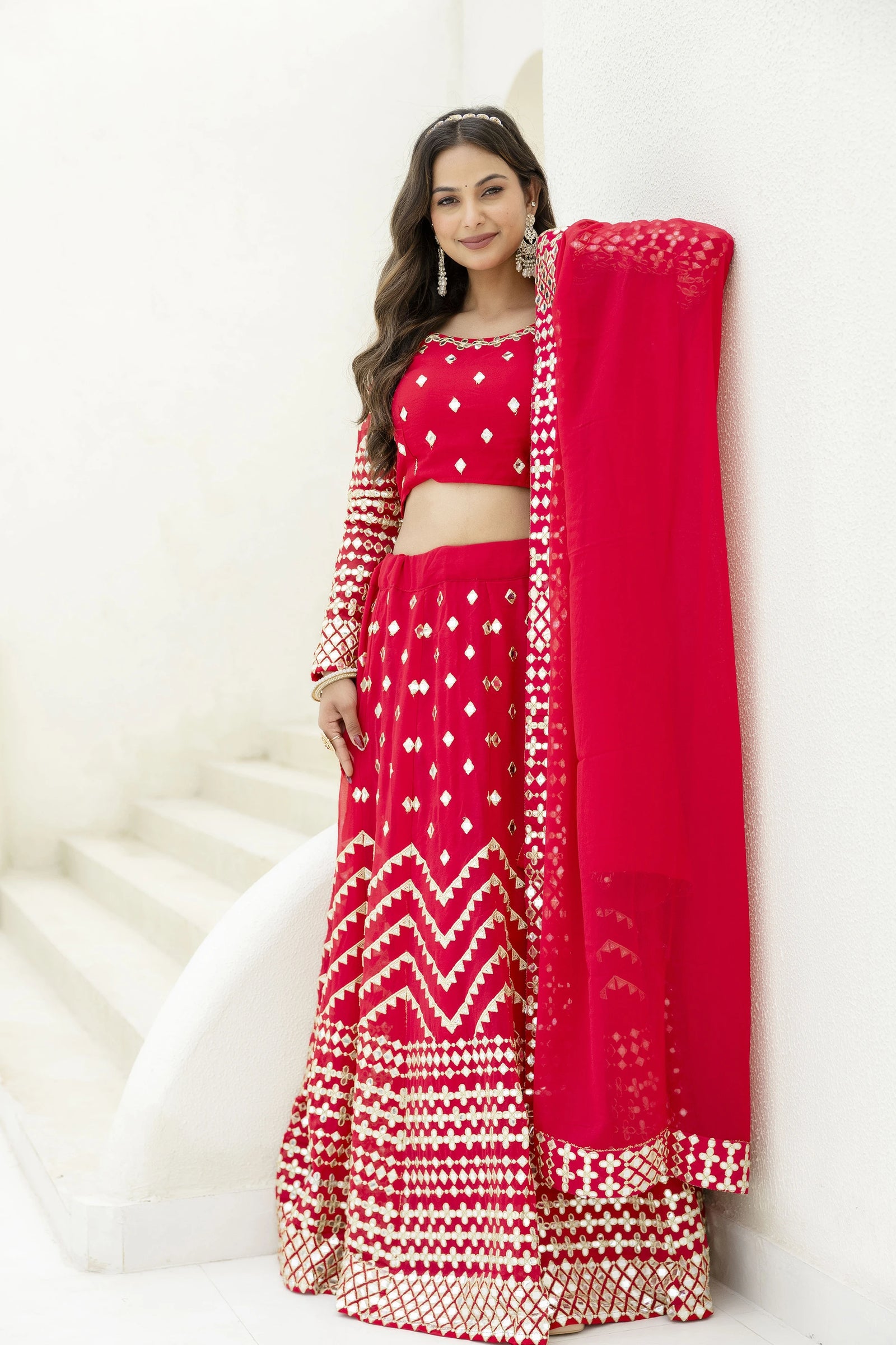 Woman wearing a red traditional outfit with white patterns on a white background