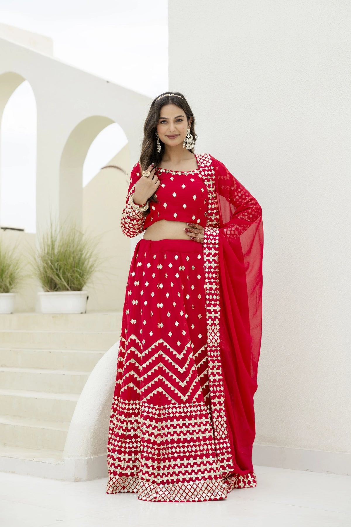 Woman in a red and white traditional outfit standing on a staircase.