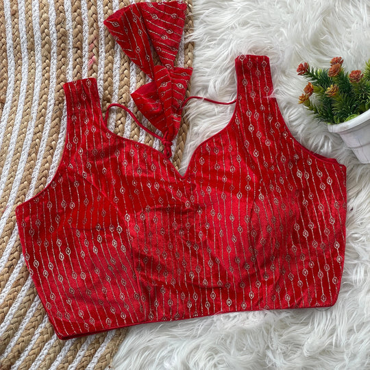 Red patterned top on a textured surface with a decorative plant in the background