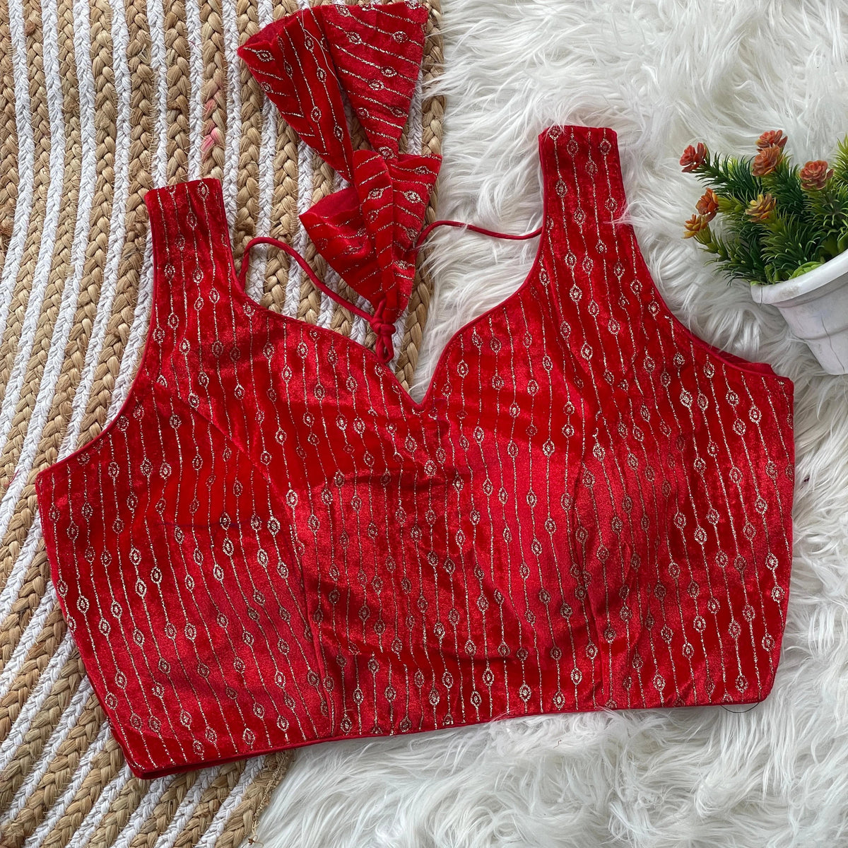 Red patterned top on a textured surface with a decorative plant in the background