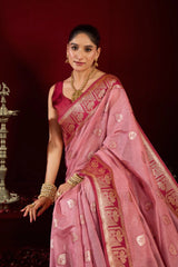 Woman in a pink saree with gold patterns against a dark background