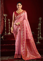 Woman wearing a pink saree with a red blouse against a dark background