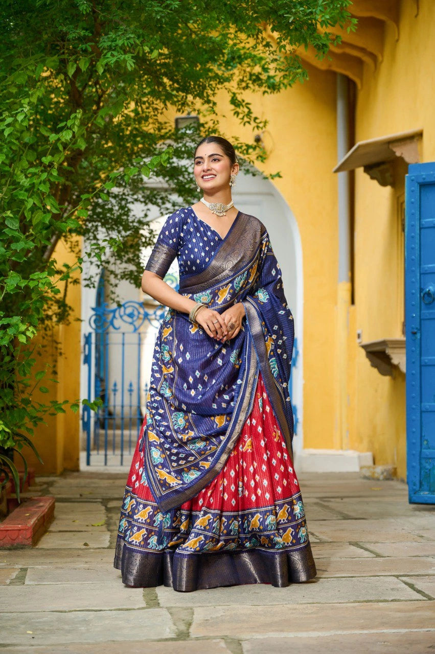 Woman in a colorful saree standing in front of a yellow wall with blue accents.
