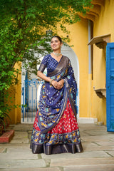 Woman in a colorful saree standing in front of a yellow wall with blue accents.