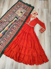 Red traditional dress with long sleeves and intricate patterns on a wooden floor.