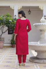 Woman in a red outfit standing in an outdoor setting with decorative elements.