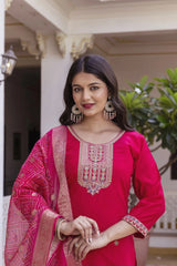 Woman wearing a pink traditional outfit with intricate designs, standing outdoors.