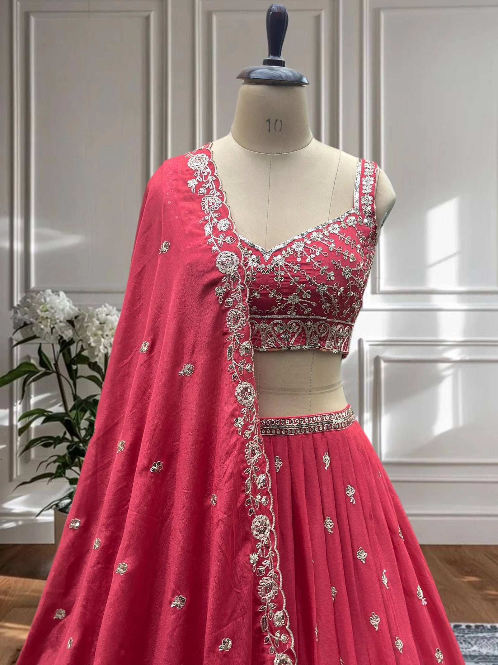 Red embroidered lehenga on a mannequin against a neutral background