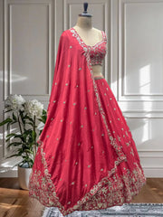 Red embroidered lehenga on a mannequin against a white paneled wall.