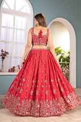 Woman in a red embroidered traditional outfit standing in a bright room with large windows.