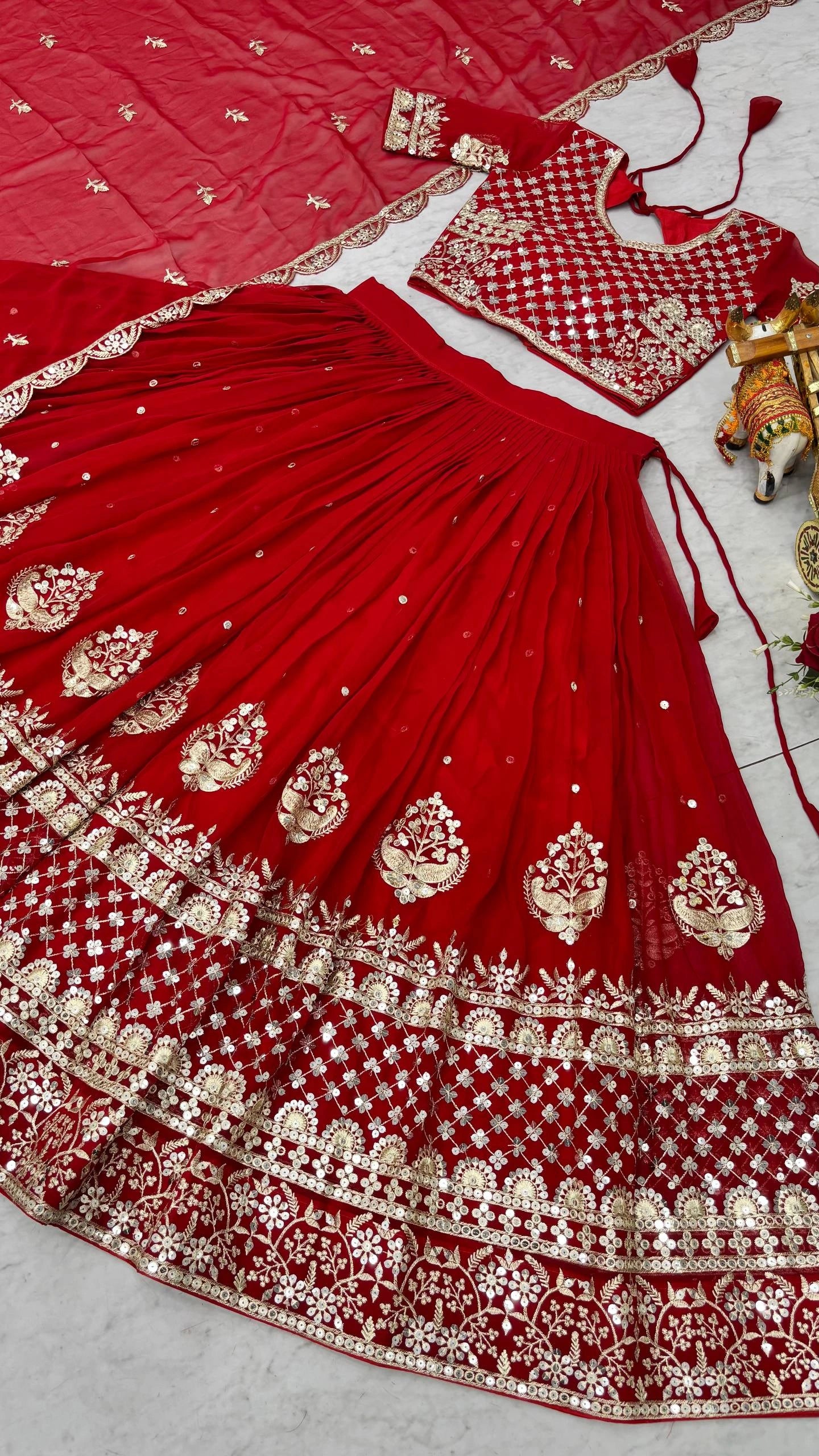 Red embroidered traditional outfit with gold details on a light gray background
