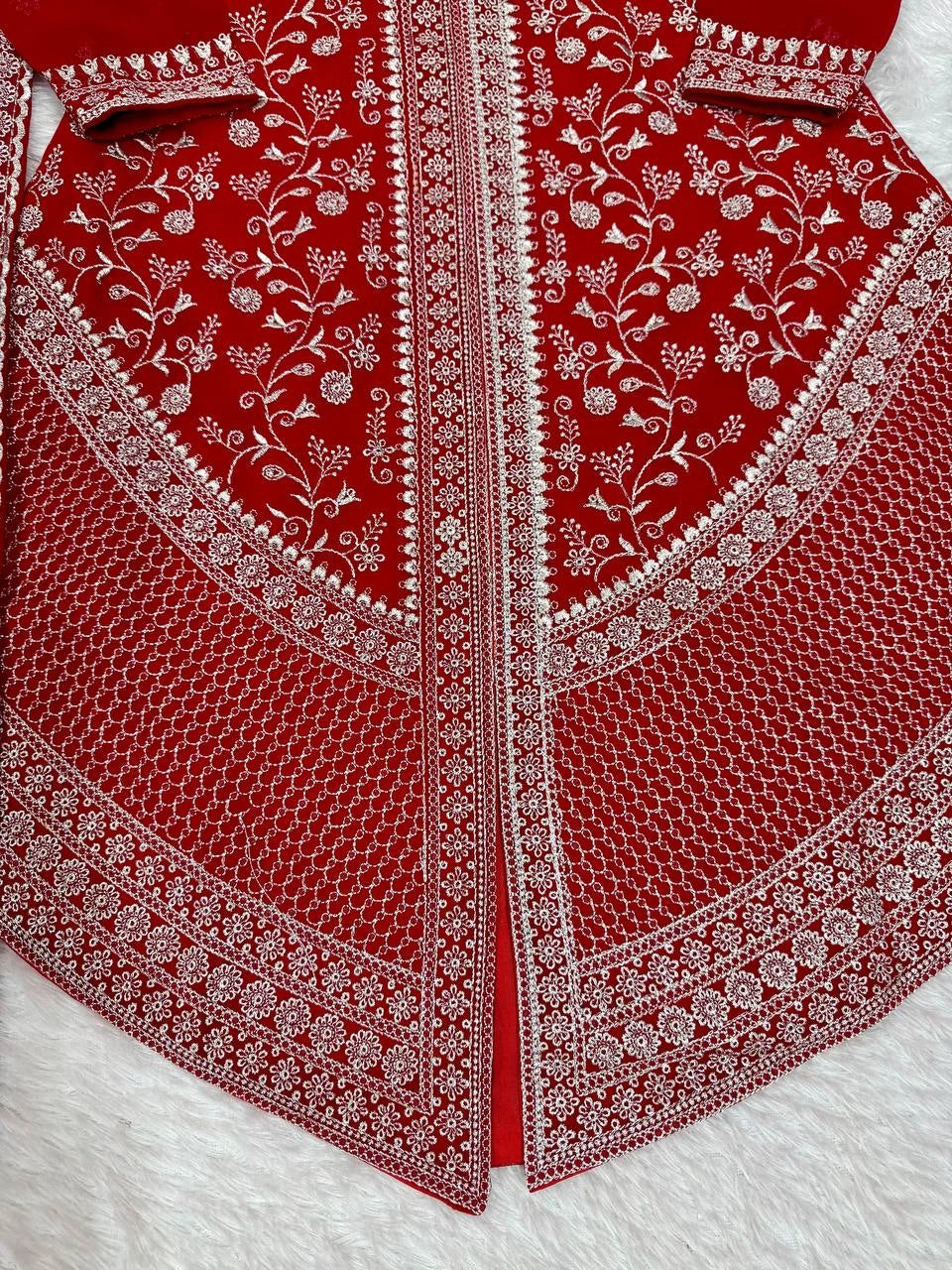 Red fabric with intricate white embroidery on a white background