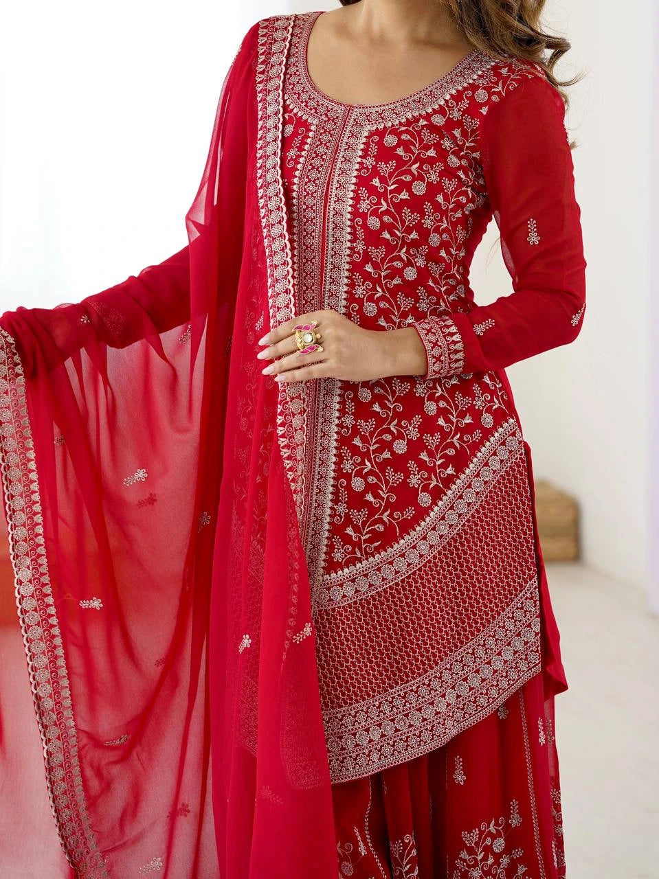 Red embroidered traditional outfit with a sheer pink dupatta on a white background