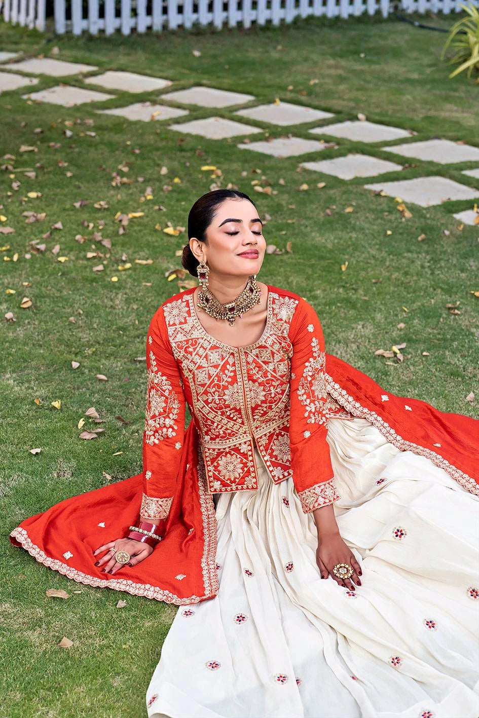 Woman in a red and white traditional outfit sitting on grass