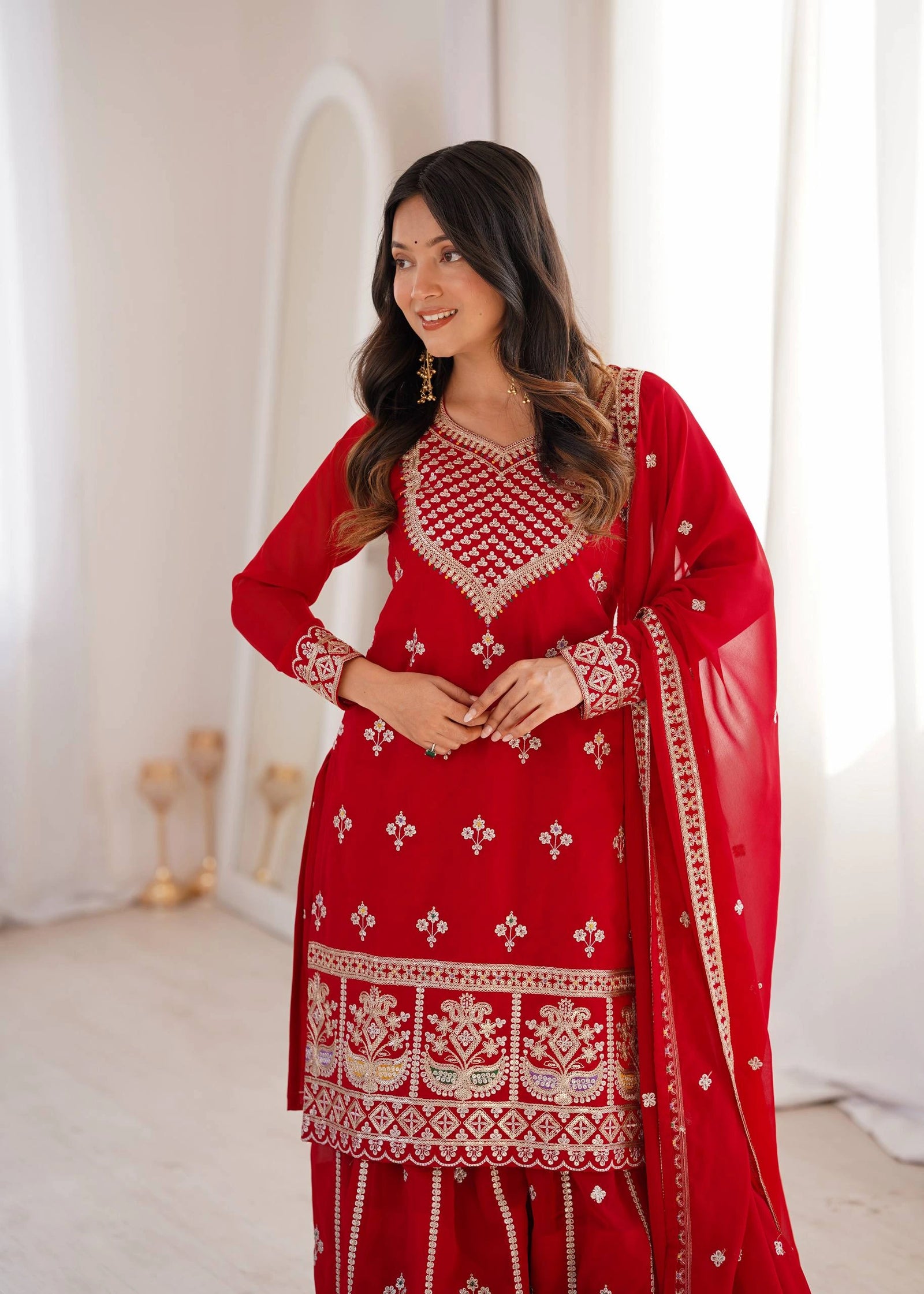 Woman wearing a red embroidered traditional outfit with a white background