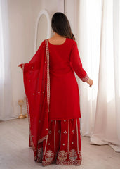 Woman wearing a red traditional outfit with a matching dupatta in a well-lit room.