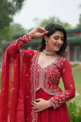 Woman in a red traditional outfit with intricate embroidery outdoors.