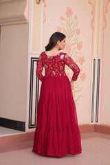 Woman wearing a red traditional outfit with floral patterns in an indoor setting.