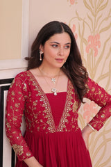 Woman wearing a red embroidered outfit with a neutral background