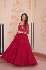 Woman wearing a red traditional outfit with gold details against a decorative wall.