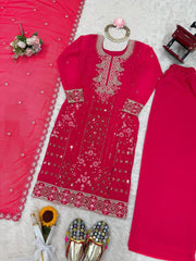 Pink embroidered traditional outfit with accessories on a textured surface